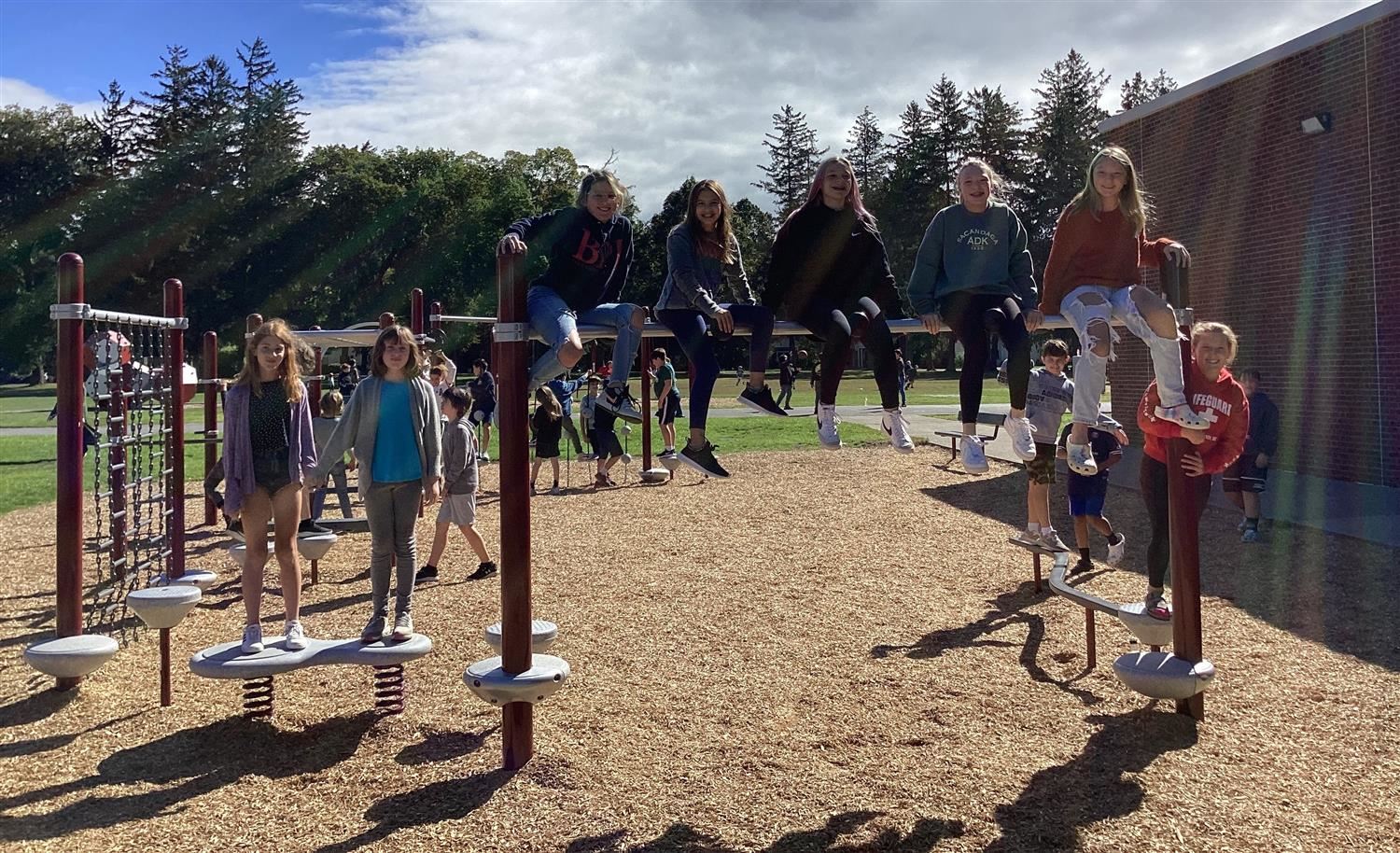  Students stand and sit atop the new playground equipment.